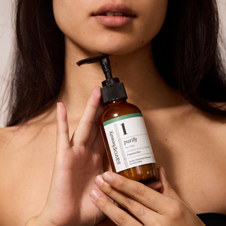 Person holding a bottle labeled 'purify' by Savor Beauty