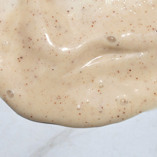 Close-up texture shot of pearl cleansing cream. It's beige, creamy  with specks on a white background