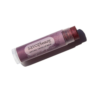 Pomegranate Passion tinted lip balm laying against white background.