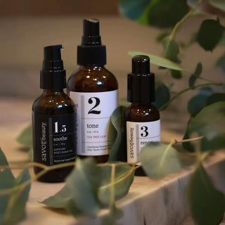 Sapphire Post Shave Gel Tea Tree Toner and Pumpkin Seed Serum on a gray marble countertop surrounded by ivy foliage